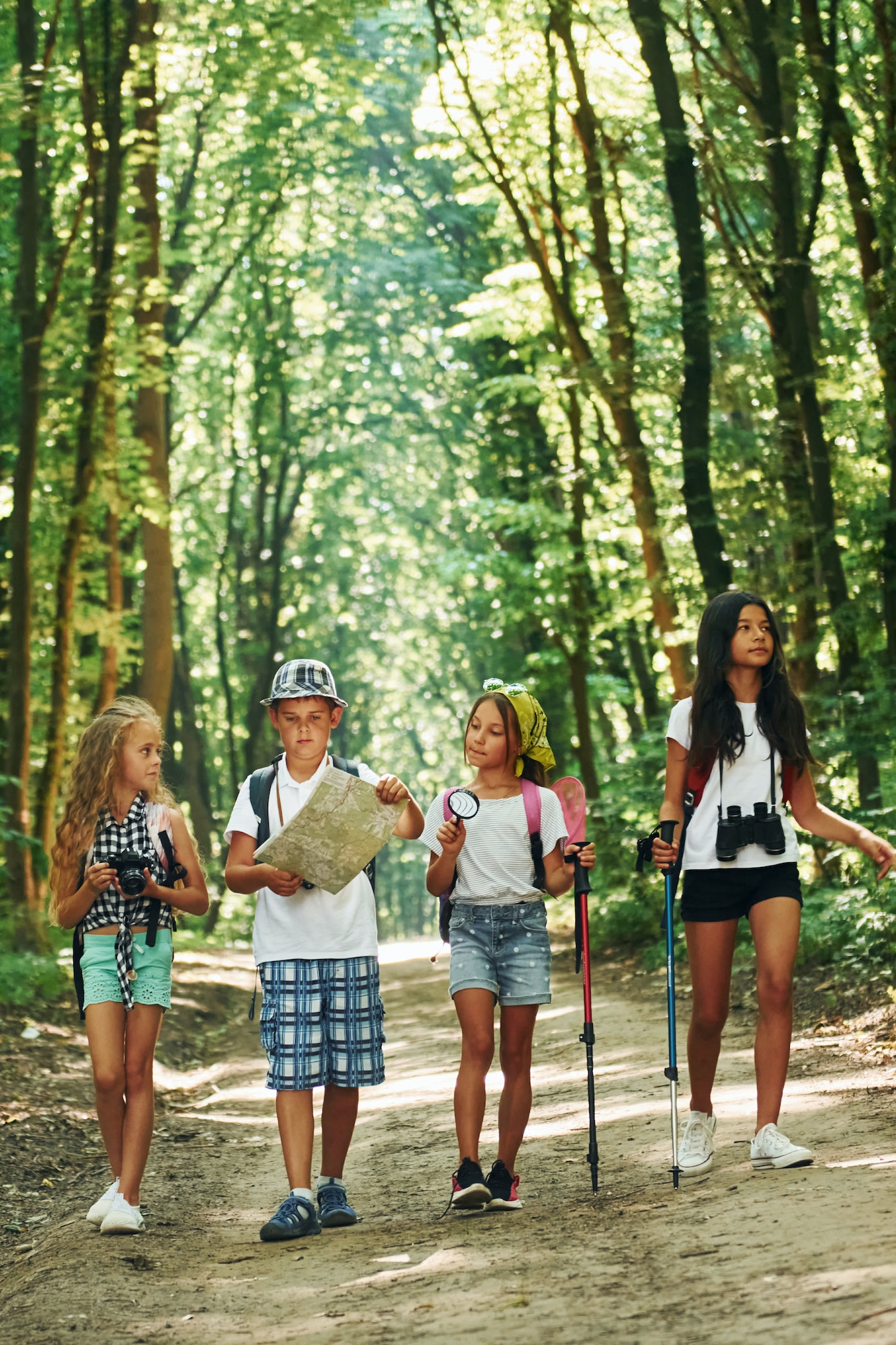 With map. Kids strolling in the forest with travel equipment